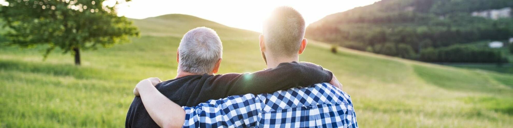 Vater und Sohn umarmen sich, mit Blick auf eine schöne Landschaft.