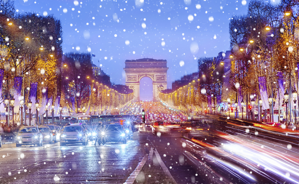 Arc de Triomphe in Paris im Winter mit Schneefall und beleuchteter Champs-Élysées