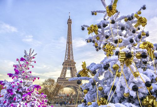 Eiffelturm in Paris im Winter mit schneebedeckten, festlich geschmückten Bäumen im Vordergrund