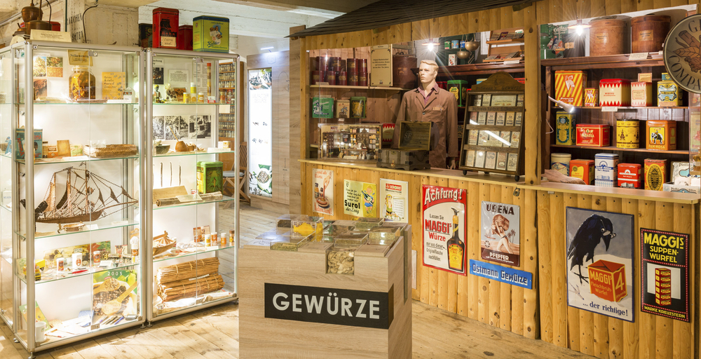 Ausstellungsraum im Gewürzmuseum Hamburg mit historischen Verpackungen, Gewürzdosen und Ladenregalen zur Geschichte des Gewürzhandels