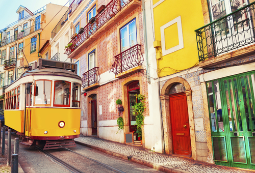 gelbe Straßenbahn in einer bunten Gasse von Lissabon