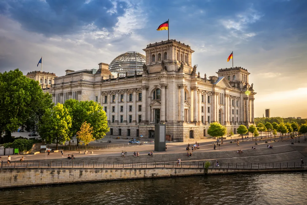 Reichstagsgebäude in Berlin bei Sonnenuntergang mit deutschen Flaggen.