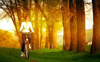 Eine Frau sitzt auf einem Fahrrad und fährt durch den Wald.