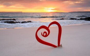Ein Herz, das im Sand liegt, mit Blick auf das offene Meer